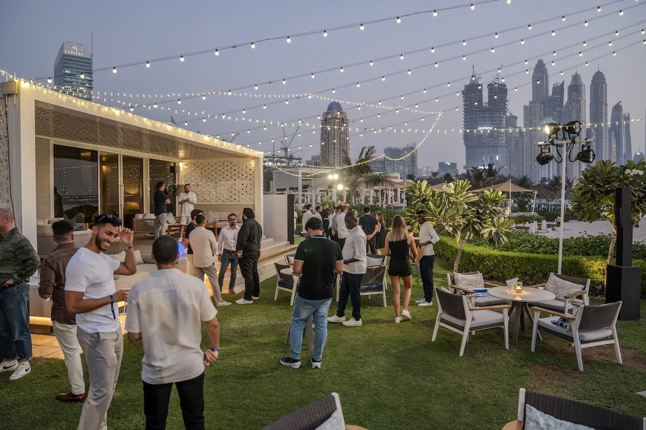 Guests networking on the lawn at dusk with the city skyline behind